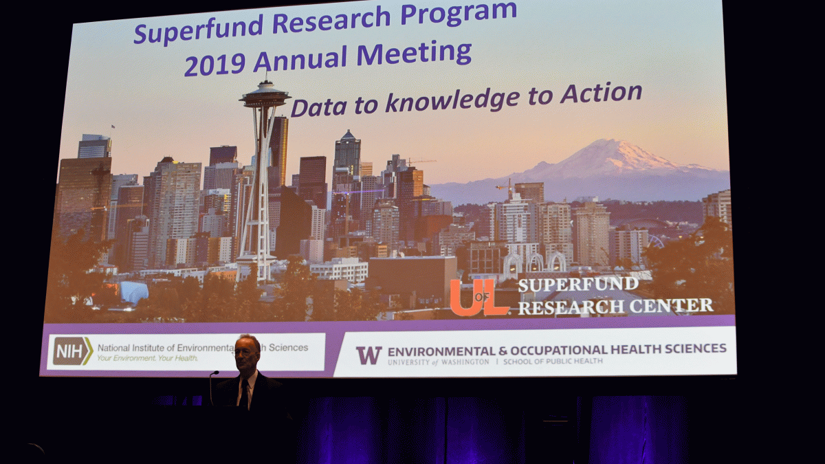 UW SRP Director, Evan Gallagher stands in front of a slide reading "Superfund Research Program 2019 Annual Meeting: Data to Knowledge to Action"