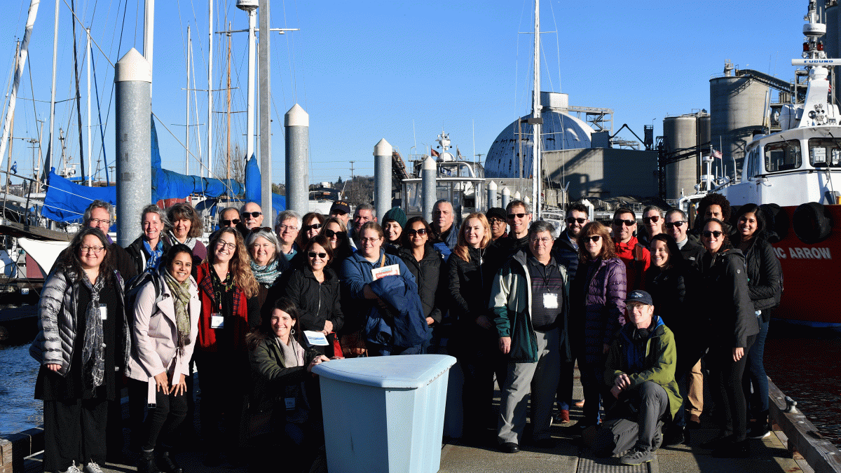 A group of boat tour participants poses on the marina dock.